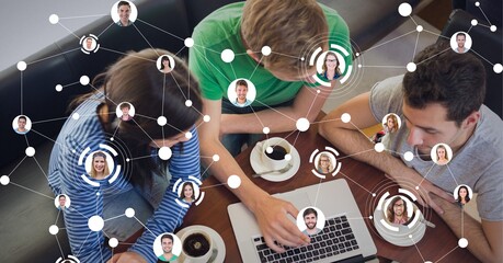 Network of profile icons against group of students using laptop at cafe