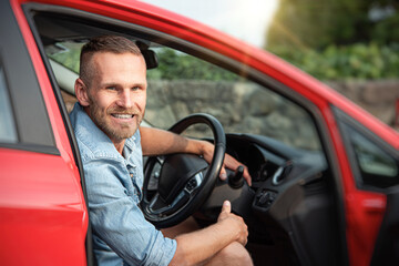 Man with a beard driving a car.