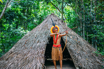 Indian from the Pataxó tribe using a bow and arrow. Brazilian Indian with feather headdress and...
