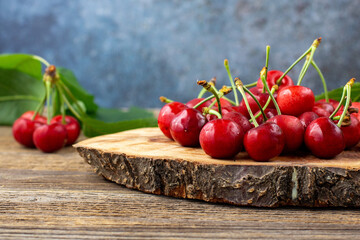 bunch of ripe sweet cherries with green leaves on wooden background