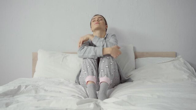 frustrated woman in pajamas sitting on bed