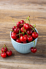 Ripe wet sweet cherries with drops in a blue bowl