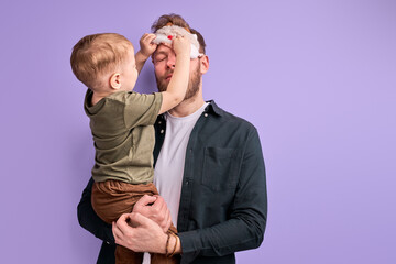 Young father in eye mask for sleeping, stand holding kid boy in hands, want to sleep in the morning