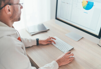 Finance asset manager man in eyeglasses using modern computer with a wireless keyboard and mouse...