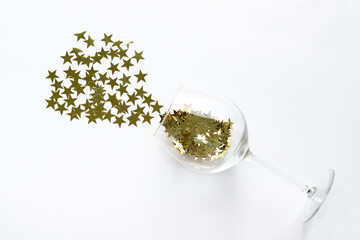 Christmas flat lay champagne glass poured out golden stars confetti with copy space.