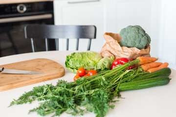 Fresh vegetables for salad on a kitchen table at home. Raw food diet and healthy eating concept.