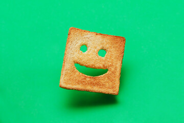 Funny smiling bread toast on a green background. Good mood, positive emotions, joy, happiness, good...