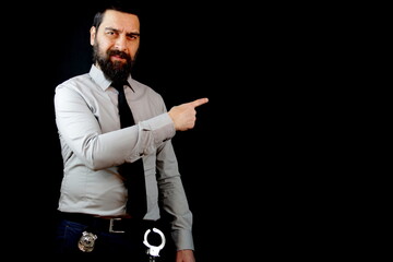 Fototapeta na wymiar Detective smiling standing looking at the camera pointing with hand and finger to the side. Isolated on black background. 