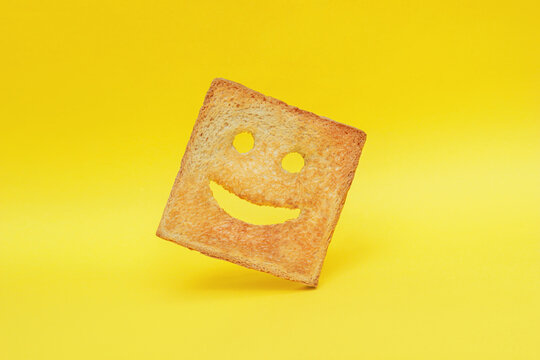 Funny smiling bread toast on a yellow background. Good mood, positive emotions, joy, happiness, good morning, delicious breakfast for kids