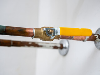 Water shut off valve. Copper plumbing pipe with brass water supply valve and yellow stopcock handle.