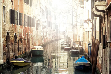 Fototapeta na wymiar View of narrow canal between old buildings in foggy morning in Venice