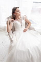 Fototapeta na wymiar Beautiful bride in a beautiful wedding dress poses on the background of a hotel room