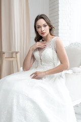 Fototapeta premium Beautiful bride in a beautiful wedding dress poses on the background of a hotel room