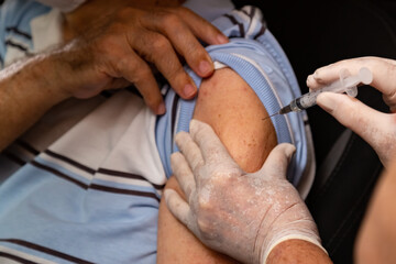 Homem idoso dentro do carro sendo vacinado por drive thru.