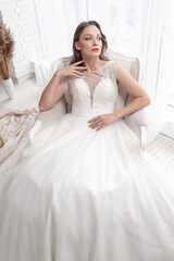 Naklejka na ściany i meble Beautiful bride in a beautiful wedding dress poses on the background of a hotel room