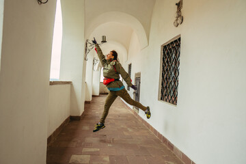 The corridor. A woman is jumping against the background of a long vintage corridor.