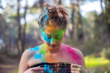 Young attractive woman at the Holi color festival of paints in park. Having fun outdoors. Multi Colored powder colors the face. Close Up portrait, people. Copy Space.