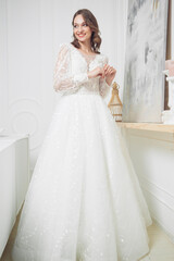 Beautiful bride in a beautiful wedding dress poses on the background of a hotel room
