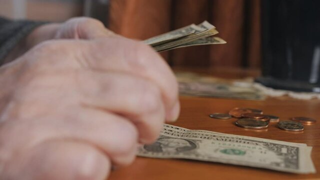 An elderly woman counts the remaining money. Economic crisis, poverty of the elderly.