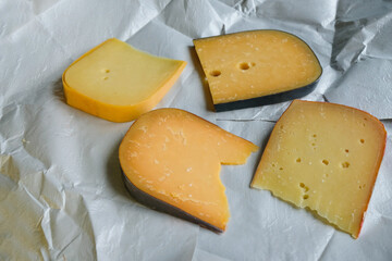 Different kinds of delicious cheeses on waxed wrapping paper. 