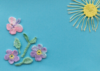 On a aquamarine background is a composition of crocheted products. Imitation of a spring or summer...