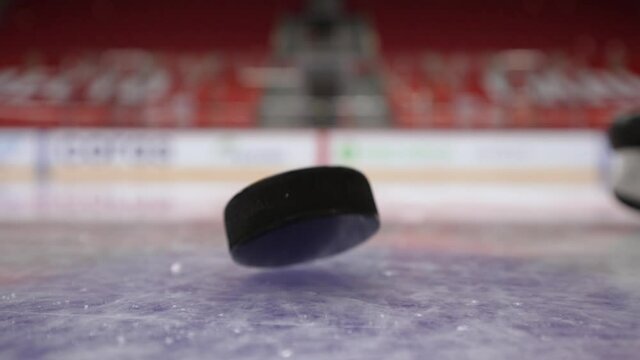 Close-up of puck falling on ice. Action. Puck slowly and epically falls to ice. Mesmerizing puck drop before impact. Sports and hockey