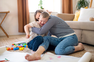 Single mother with down syndrome child at home, having fun when playing.