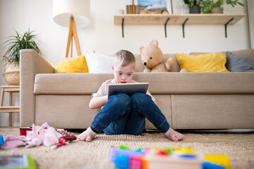 Down syndrome child using tablet at home.