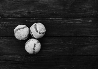 Old baseballs on wood background in black and white with copy space for nostalgia sport.