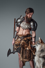 Furious northern soldier holding a double axe and posing with a wolf