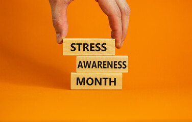 Stress awareness month symbol. Wooden blocks with words 'Stress awareness month'. Beautiful orange...