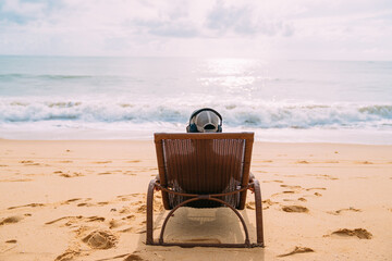 Fototapeta na wymiar summer holidays, technology and internet concept. latin american man sitting on the beach chair, listen music with headphone and sunning on the beach