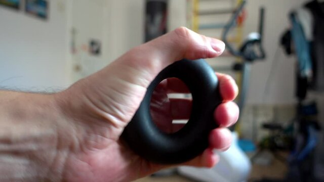 Man is training with the hand grip strengthener. Expander. Sporty wrist builder for everyday trainings.