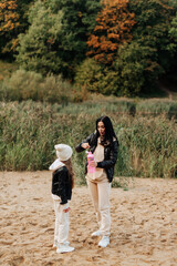 mom and daughter in black leather jackets blow bubbles on the sand