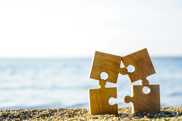 four 4 wooden puzzles standing on sand beach on on blue sea and sky background. family on resort...