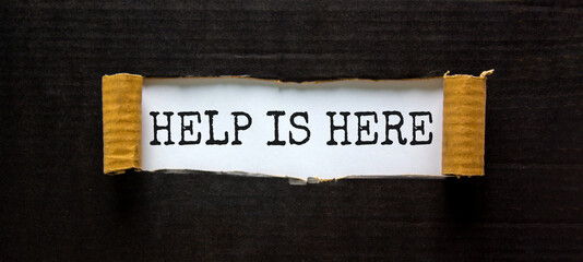 Support and help is here symbol. Words 'help is here' appearing behind torn black paper. Beautiful black background. Business, support and help is here concept. Copy space.