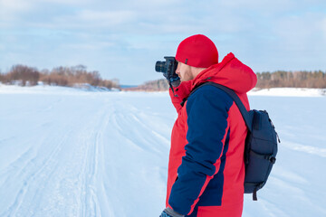 Fototapeta na wymiar Photographer on a winter landscape with a camera in his hands.