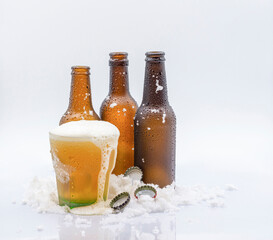 THREE EMPTY COLD BEER BOTTLES OF BEER AND ONE COLD GLASS GLASS FULL OF VERY COLD BEER