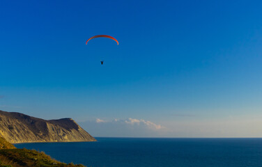 Paragliding in the sky. Paraglider tandem flying over the sea with mountains at sunset