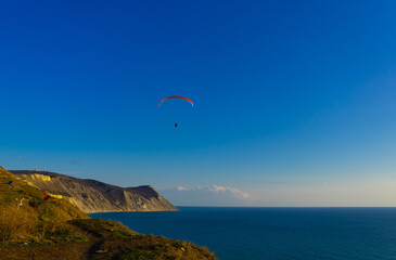 Paragliding in the sky. Paraglider tandem flying over the sea with mountains at sunset