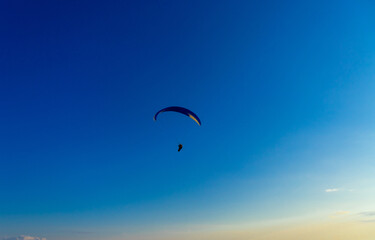 Paragliding in the sky. Paraglider tandem flying over the sea with mountains at sunset