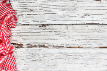 Top view of an empty white wooden picnic table and crumpled red and white gingham tablecloth at the...