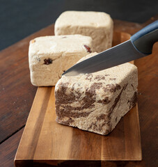 Halva almond nuts and cocoa pieces on wooden table background