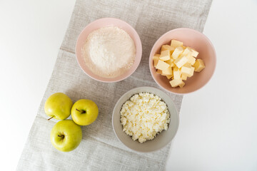 Main ingredients for Apple Pie. Plates with flour, butter, cottage cheese and apples. Top view