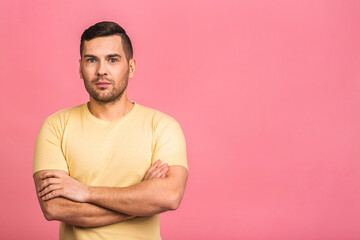 Portrait with copy space, empty place of stunning, sexy, smiling, cool man in casual having his arms crossed, looking at camera, isolated on pink background.