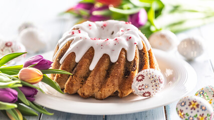 Festive easter marble cake with icing sugar hand-decorated eggs and spring tulips