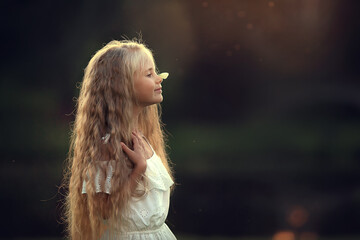 A butterfly is sitting on a nose of beautiful long-haired girl. Image with selective focus and toning