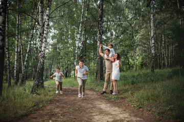 Fototapeta premium Two elder boys are running a race, their parents and younger brother are cheering for them. Image with selective focus and toning