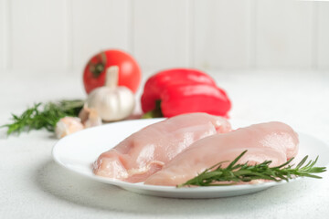 Chicken fillet on a plate with herbs and vegetables on a light background.