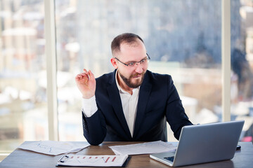 The corporate madman is sitting at the computer in the office and going crazy, the emotional portrait of the man at the table. Crazy worker at his workplace